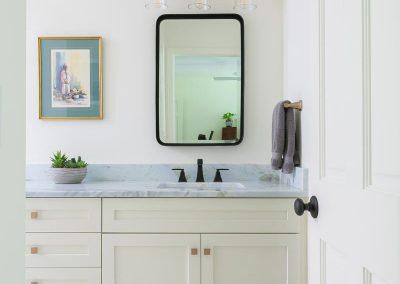 Open door leading to bathroom with vanity and custom cabinetry.
