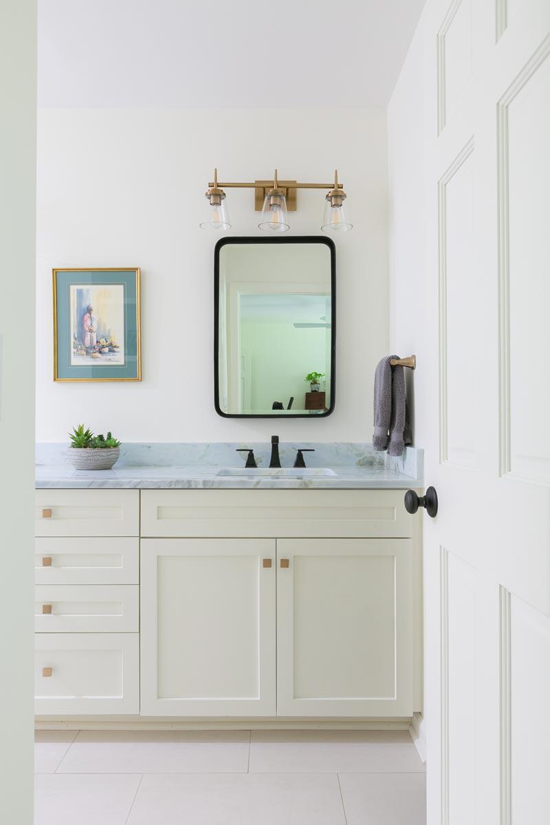 Open door leading to bathroom with vanity and custom cabinetry.