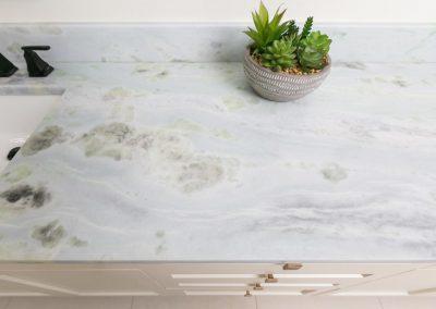 Beautiful stone counter top with potted succulent next to sink.