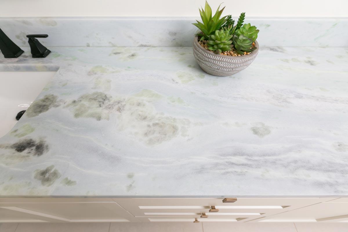 Beautiful stone counter top with potted succulent next to sink.