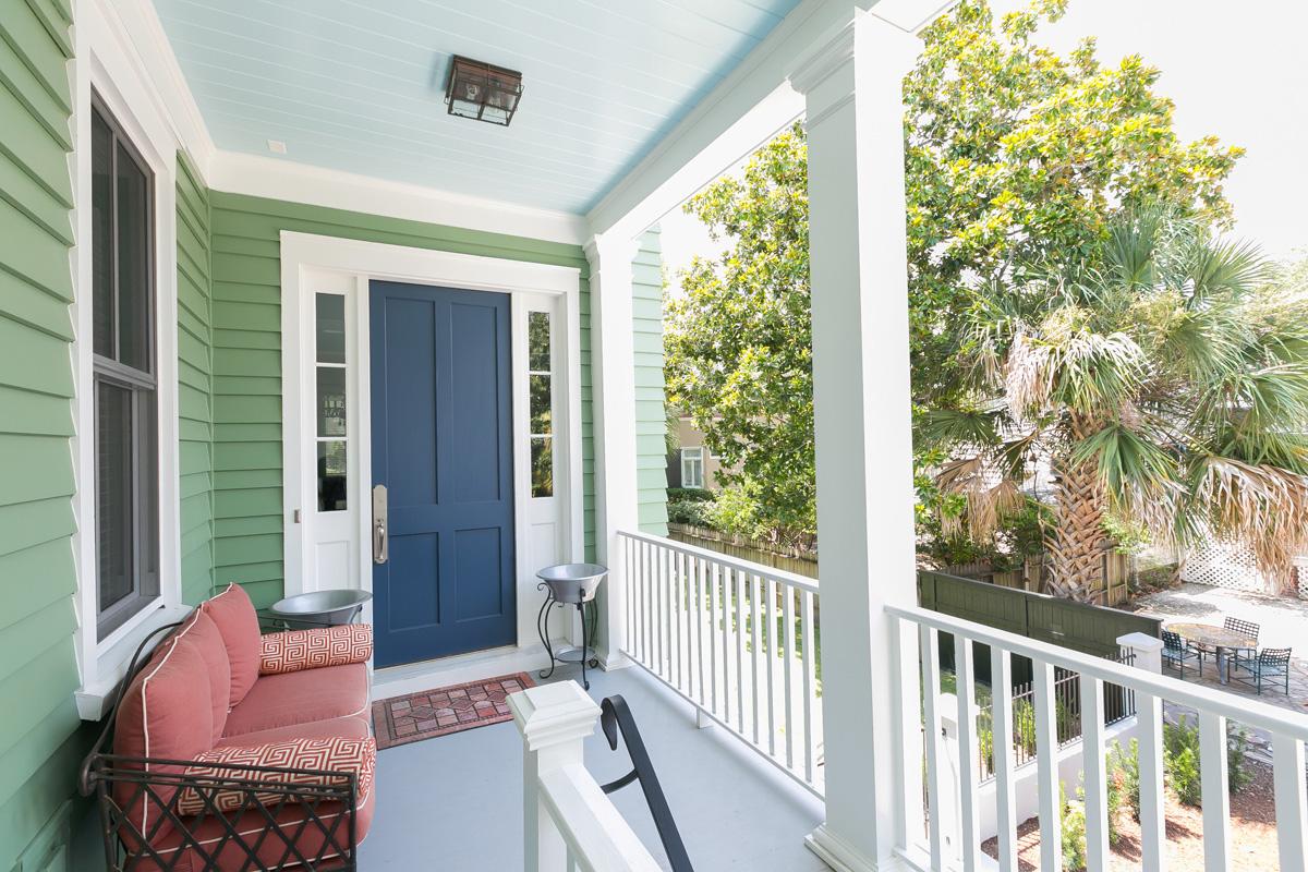 Second level entry of downtown Charleston, SC row house with sidelights, green siding, navy door and powder blue traditional porch ceiling.