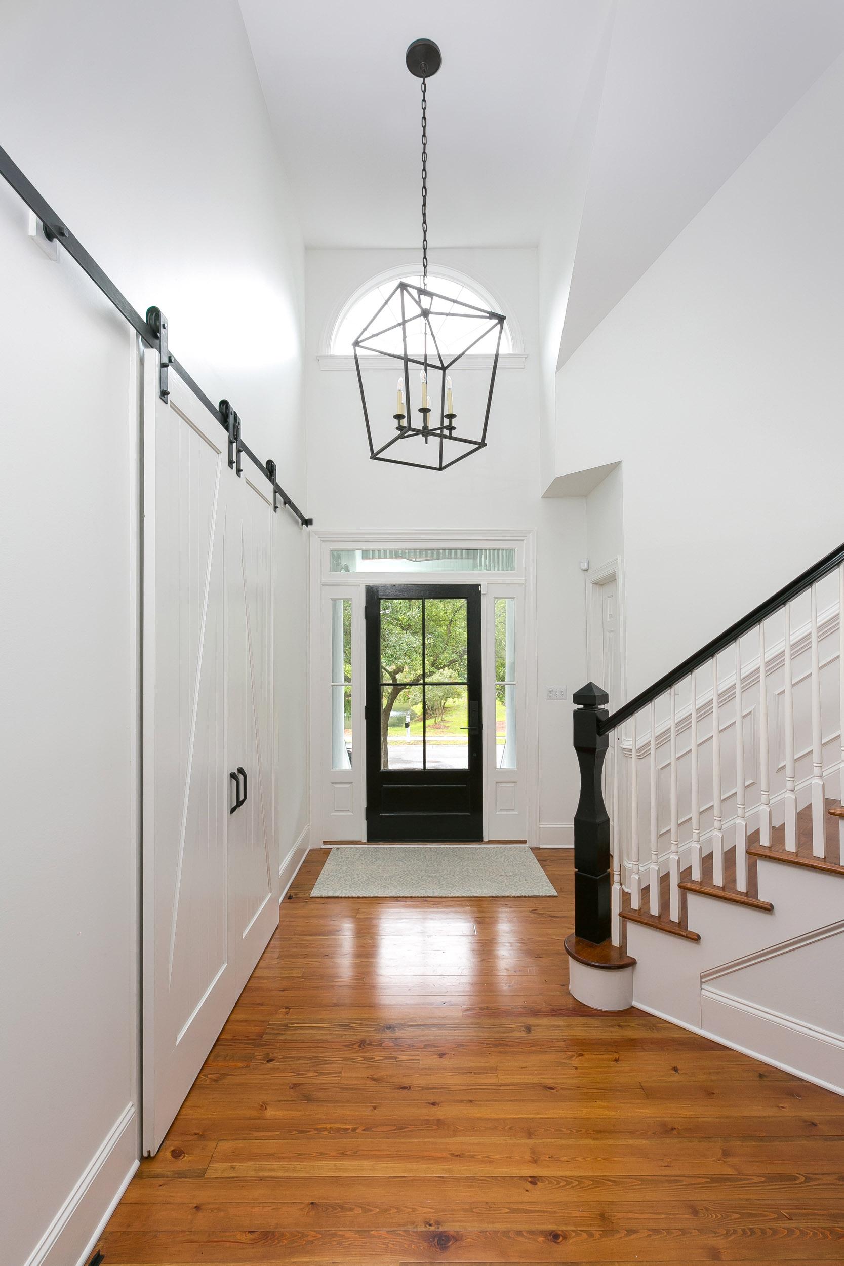 Entryway with front door, sidelights and transom. Custom banister and stair leading to upper level. Wainscoting and custom trim and sliding barn doors.