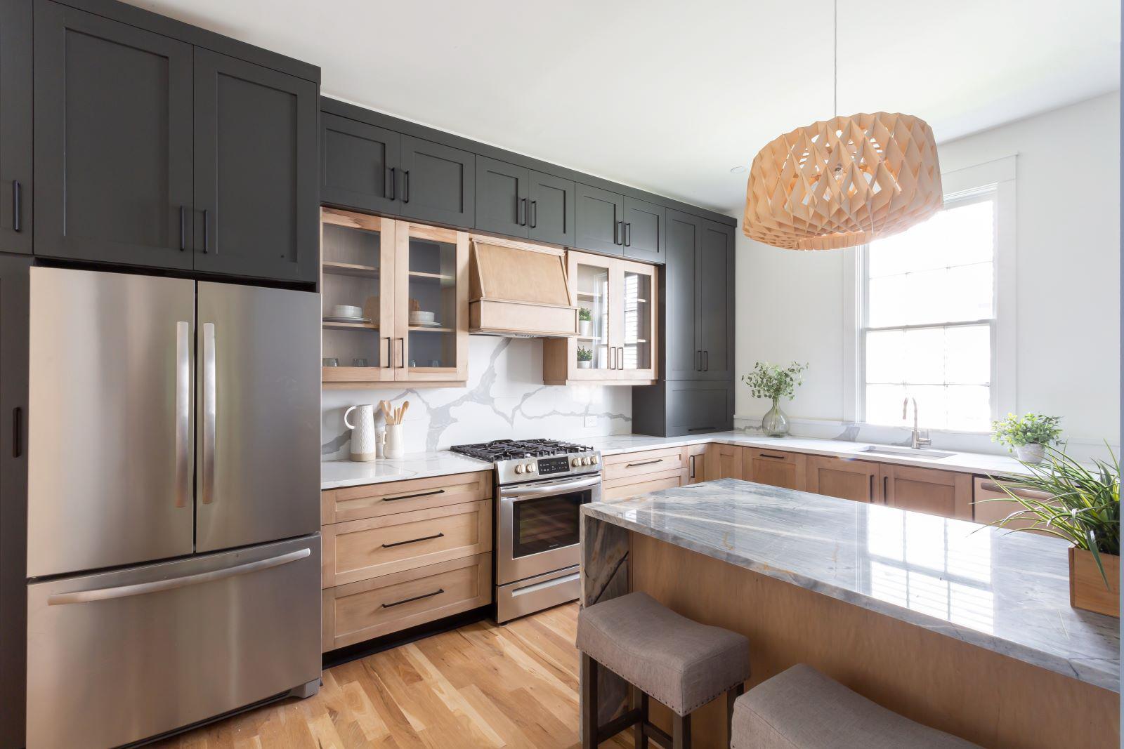 Custom home kitchen addition with custom cabinetry in beautiful contrasting natural stained and painted charcoal gray accents, marble countertops and stainless steel appliances.