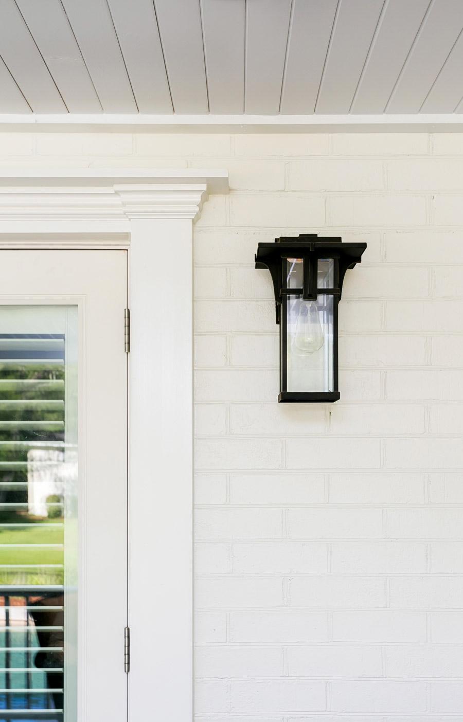 Outdoor sconce on whitewashed brick home with custom molding.