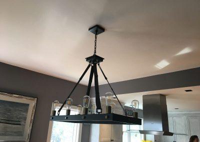 Eight light rectangular industrial looking chandelier hanging above a dining table.