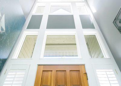 Vaulted entryway with windows going up 3 stories, ornate "orbit" designed light fixtures hang down in the middle as well as sconces on either side.