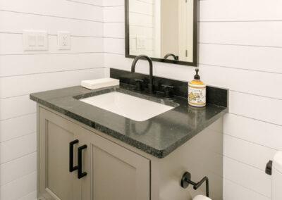 Gray and black vanity in powder room and wall mounted lighting.