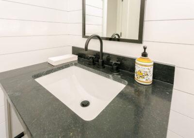 Black marble vanity counter against shiplapwalls.