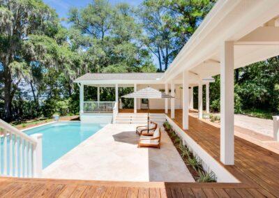 Tiled pool patio with outdoor loveseats and umbrella.