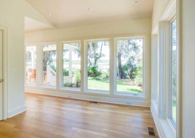 Large hallway with beautiful light hardwood flooring and panoramic windows looking out onto a covered deck and river view.