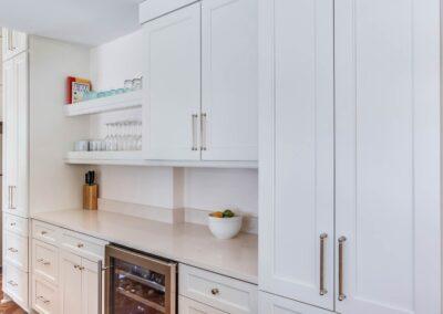 Custom cabinets with streamlined hardware, wine fridge and modern open shelving with glassware.