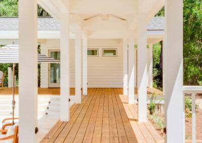 Looking down the length of a deck walkway with columns on either side and pitched roof covering.