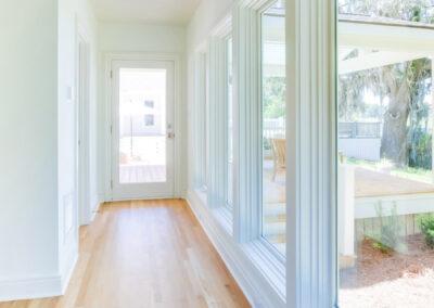 Indoor hallway with floor to ceiling windows and light wood flooring.