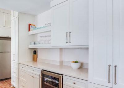Custom kitchen cabinetry with wine fridge, stainless appliances, open shelving and brick floor.