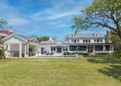 Grand view of rear of beautiful brick home with custom detail in the cabana, pool deck, outdoor stone fireplace and screened porch.