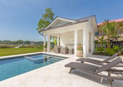 Covered patio and pool deck with river view and dock in the distance.