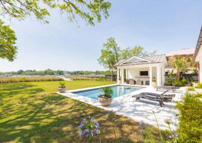 Beautiful pool deck overlooking marsh and river view with dock in the distance.