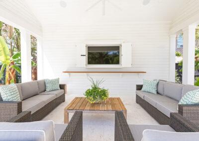 Large covered patio with comfortable furnishings, custom aesthetics and tropical plants surrounding.