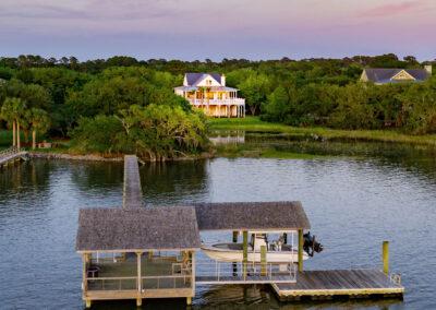 Beautiful dock with covered seating, floating dock and covered boat lift leading back to property with custom home in distance.
