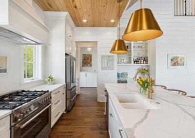 Custom kitchen with white marbled countertops, natural wood paneled ceiling, ship lap walls, 6 burner gas range, kitchen island and built-in wet bar.