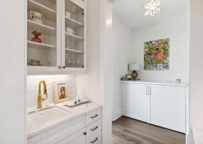 Wet bar and pantry with decorative light fixture and custom cabinets.