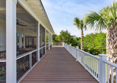 Open air deck on custom home's back porch looking onto screened-in section and covered seating area.