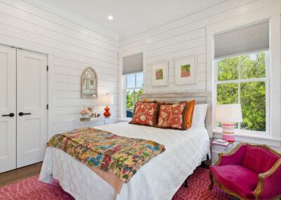 Ship lap walls in a bedroom with french closet doors and large windows.