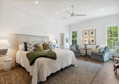 Master bedroom with ship lap walls, ceiling fan, large windows and custom decor.