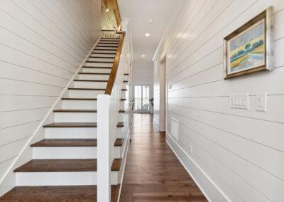 Main staircase view toward back of the house from fully shiplapped foyer, hallway and into rest of the home.