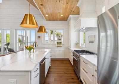 Beautiful view from bright and naturally lit kitchen with pendant lights on the left and refrigerator on the right.