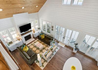 looking down from upstairs loft into living room/dining room combo. All windows and doors lead to the exterior porch.