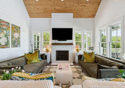Living room with eclectic decor, brick fireplace, natural wood ceiling and ship lap walls.
