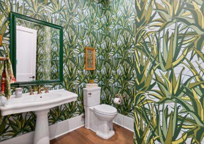 Cactus wallpapered powder room with vanity and commode pictured.