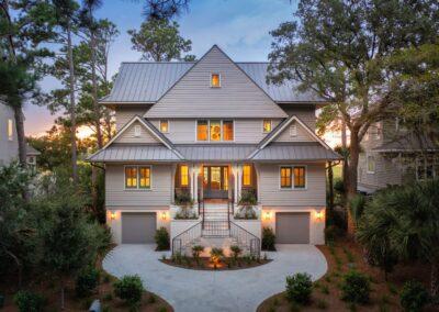 Aerial view of the exterior of a beautiful custom home on Kiawah with 4 levels, lit and at dusk.