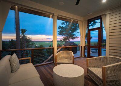 Kiawah Island custom home screened in porch overlooking the open air deck with grill and pool and the sunset marsh beyond.