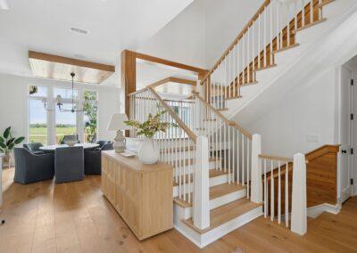 Main level of home with stairs going up and down. Dining area in background witha. view to the marsh beyond.